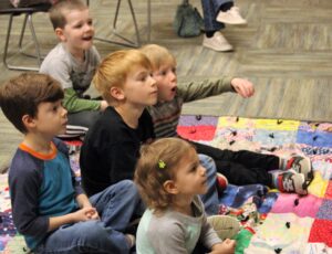 Five children sitting on the floor enjoy story time