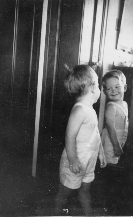 Borden as a young boy smiling as he looks at himself in a mirror.