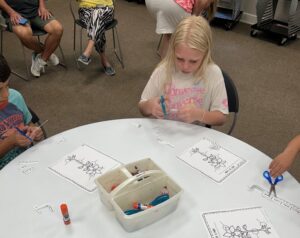 Children are coloring the parts of a plant on a diagram.