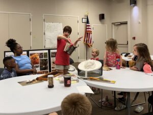 A beekeeper is explaining to children and parents the importance of bees as pollinators