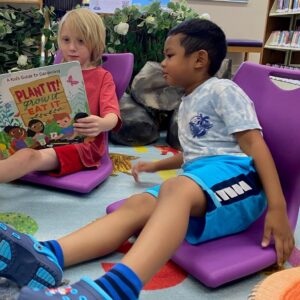 Two children use floor recliners in the Children's room