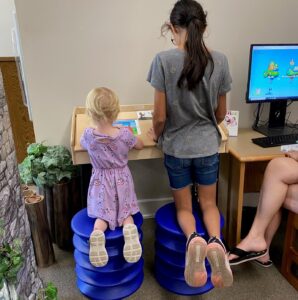 Two children kneel on wobble stools in the Children's room.